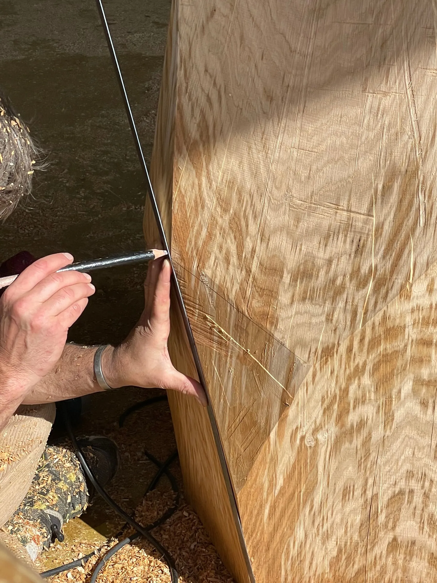 Mains traçant un repère sur une pièce de bois sculptée